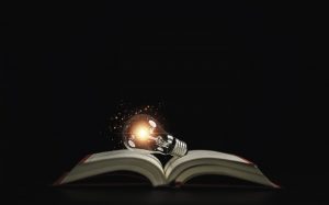 Lightbulb glowing on book over dark background for creative thinking idea after reading and study concept.